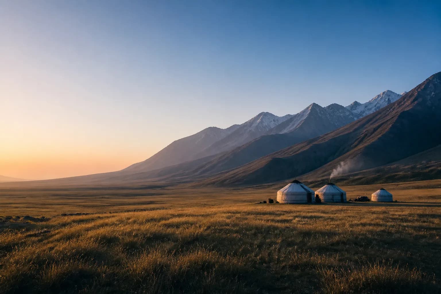 Yurt camp below a mountain valley at dawn